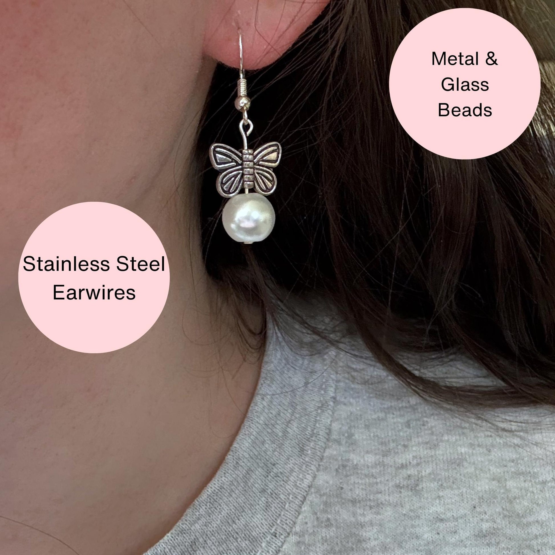 A pair of silver earrings butterfly earrings in an ear. The photo also has text explaining that the earrings are made with metal and glass beads and uses stainless steel earwires. The earrings feature metal butterflies and a pearl under the butterfly.